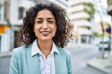 Wall Mural - Young hispanic business woman wearing professional look smiling confident at the city