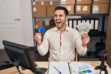 Sticker - Young hispanic man with beard working at small business ecommerce holding banknotes and credit card angry and mad screaming frustrated and furious, shouting with anger. rage and aggressive concept.