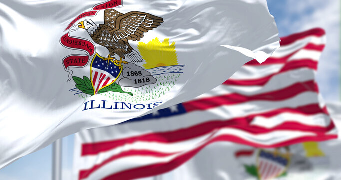 the illinois state flag waving along with the national flag of the united states of america