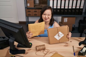 Canvas Print - Hispanic girl with down syndrome working at small business ecommerce winking looking at the camera with sexy expression, cheerful and happy face.