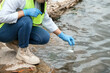 © Pornpimon - Female environmentalist hands in glove collects water samples from a river to explore and testing for infections. Water and ecology concept