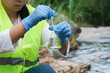 © Pornpimon - Female environmentalist hands in glove collects water samples from a river to explore and testing for infections. Water and ecology concept