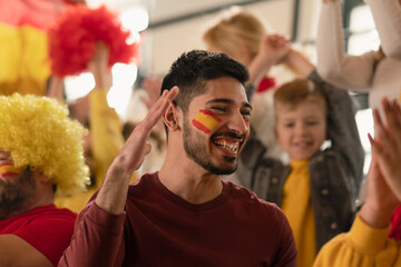 Wall Mural - Excited, happy football fans supproting spanish national team in live soccer match at stadium.