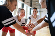 © Halfpoint - Group of young and old women in gym stacking hands together, sport team players.