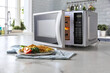 Leinwandbild Motiv Microwave oven with food on the kitchen table