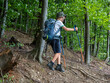© Daniel CHETRONI - Happy boy with backpack and trekking sticks hiking in mountain forest