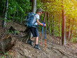 © Daniel CHETRONI - Happy boy with backpack and trekking sticks hiking in mountain forest