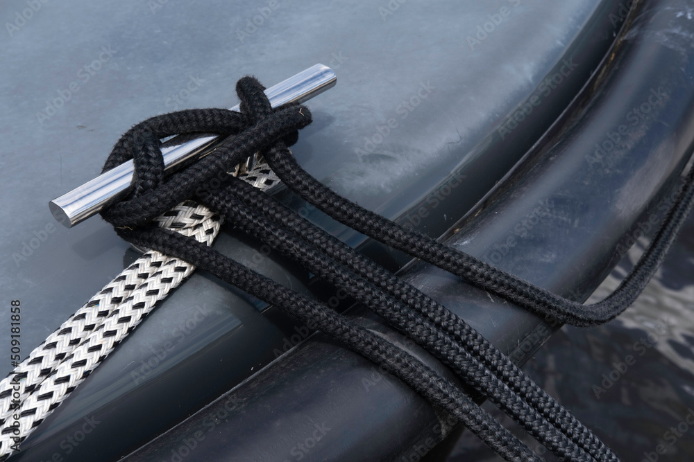 Stainless steel deck cleat with ropes around it to secure a boat to a ...