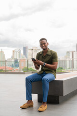 Wall Mural - Portrait of handsome young black man outdoors in city