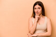 © Asier - Young hispanic woman isolated on beige background looking sideways with doubtful and skeptical expression.