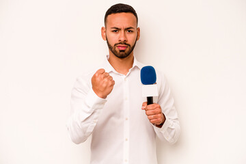 Wall Mural - Young hispanic TV presenter isolated on blue background showing fist to camera, aggressive facial expression.