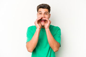 Young caucasian man isolated on white background saying a gossip, pointing to side reporting something.