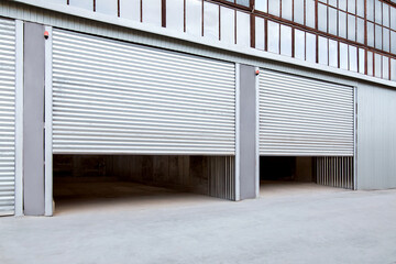 Wall Mural - Opening gray iron shutter door of garage and industrial building warehouse exterior facade with grey concrete road, side view nobody.