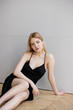 © LIGHTFIELD STUDIOS - Stylish blonde woman in dress sitting on wooden floor at home.