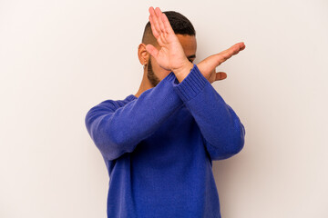 Young hispanic man isolated on white background keeping two arms crossed, denial concept.