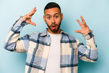 Wall Mural - Young hispanic man isolated on blue background celebrating a victory or success, he is surprised and shocked.