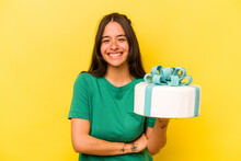 Young Hispanic Woman Holding Birthday Cake Isolated On Yellow Background Laughing And Having Fun.