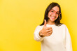 Young hispanic woman isolated on yellow background smiling and raising thumb up