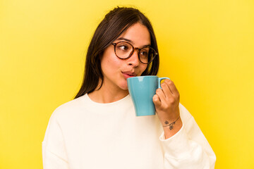 Wall Mural - Young hispanic woman holding a mug isolated on yellow background