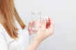 © BartLoveyou - a woman with a pill and a glass of water on a white background. close-up