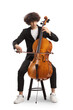 Young male artist sitting on a chair and playing a contrabass