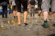 Viele Beine und Füße im Regen auf Festival, stehend, tanzend im Matsch mit Pfützen