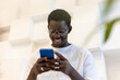 © kanashkin - African american guy with glasses typing a message on the phone.