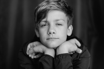 Black and white portrait of teenage boy on dark background. Low key close up shot of a young teen boy. Black and white photography. Selective focus