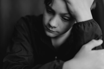  Black and white portrait of teenage boy on dark background. Low key close up shot of a young teen boy. Black and white photography. Selective focus