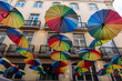 © alones - Colorful rainbow umbrellas fly in the street near buildings in Lisbon, Portugal. Concept creative idea