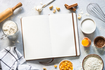 Wall Mural - Baking background with cooking book and ingredients. Flour, sugar, eggs and utensil at light stone table. Top view with copy space.