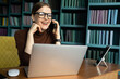 © muse studio - A woman with glasses talks a call works uses a phone in an office in a coworking space