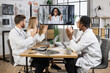 © sofiko14 - Team of multicultural doctors in white lab coats clapping hands during online video conference after successful speech of excited female scientist. Focus on african american woman on monitor screen.