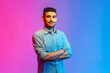 © khosrork - Portrait of calm smiling man in shirt standing with crossed arms, looking at camera with confident facial expression. Indoor studio shot isolated on colorful neon light background.