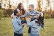 © Strelciuc - Happy family having fun outdoors and smiling. Parents carry kids in the park. Family weekend. Spring time.