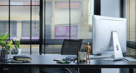 Wall Mural - Modern office with computer, coffee cup, financial document and potted plant on black wooden table.