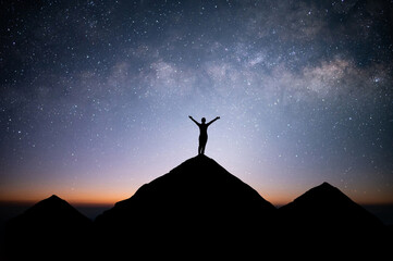 Wall Mural - Silhouette of young female traveler and backpacker standing and watched the star and milky way alone on top of the mountain. She enjoyed traveling and was successful when he reached the summit.