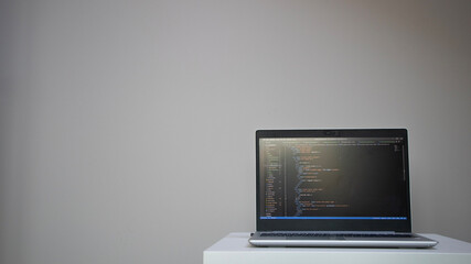 Opened laptop with code on the screen on the table