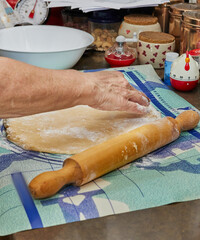 Poster - Woman rolls out the dough with rolling pin in the kitchen for making pie