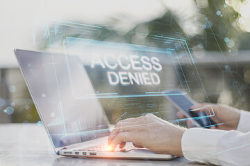 Wall Mural - Close up of businessman hands using laptop and smartphone on desktop with abstract denied access hologram on blurry outdoor background. Connection and crime concept. Double exposure.