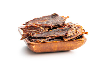 Poster - Beef jerky meat in wooden bowl. Dried sliced meat isolated on white background.