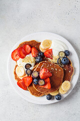 Canvas Print - Summer breakfast. Pancakes with strawberries, blueberries, banana and cream on white plate. Vegan recipe.