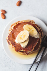 Canvas Print - Banana pancakes with syrup on white plate, gray background. Vegan recipe concept.