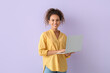 © Pixel-Shot - Pretty African-American woman using laptop on lilac background