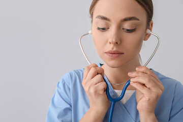 Canvas Print - Young female doctor with stethoscope on  grey background