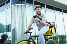 Express Delivery Courier With Insulated Bag Holding Phone On Bicycle.