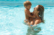 © blackday - Mother and her cute little son swimming in outdoor pool during summer vacation