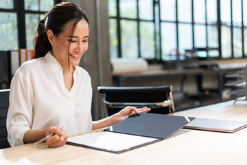 Asian business female project manager reading document report at desk in the office. work data and information. signing on business contract agreement.