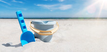 Close-up View Of Toy Bucket And Spade On Sand Beach Against Sea And Blue Sky