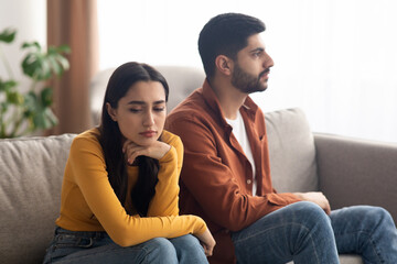 Wall Mural - Unhappy Arabic Couple Sitting On Couch Indoor, Having Relationship Problems